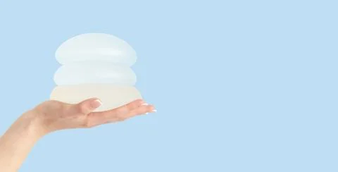 Different types of breast implants in hand on blue background. Copy space Foto stock