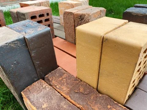 Different types of bricks stacked beautifully on green grass Stock Photos