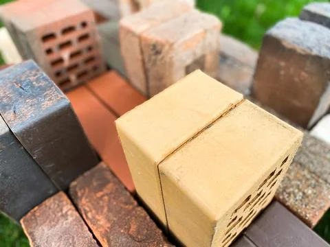 Different types of bricks stacked beautifully on green grass Foto stock