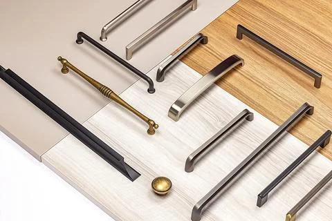 Different types of cabinet handles arranged on surfaces of wood and laminat.. Stock Photos