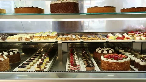 Different types of cakes and desserts in a pastry shop glass display Stock Footage 158126256