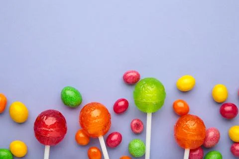 Different types of candies on purple background, copy space. Colorful birthda Stock Photos