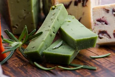 Different types of cheese are cut on a plate with rosemary Stock Photos