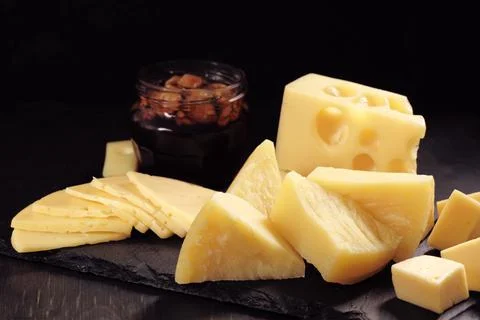 Different types of cheese cut into slices lie on stone plate Stock Photos