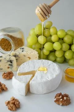 Different types of cheese, with grapes, nuts and honey on a white background. Foto stock