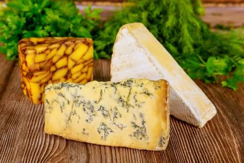 Different types of cheese with herb on wooden background. Stock Photos
