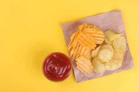 Different types of chips with a red sauce on a bright yellow background. view Stock Photos