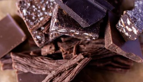 Different types of chocolate pieces on dark wood background. Stock Photos