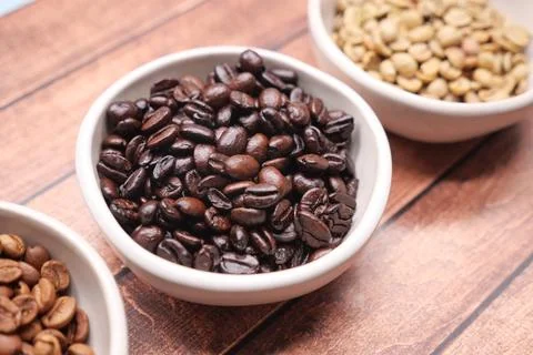 Different types of coffee beans placed in bowls on a wooden table Stock Photos