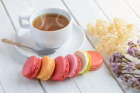 Different types color of macaroons with Cup of hot tea on white wooden backgr Stock Photos