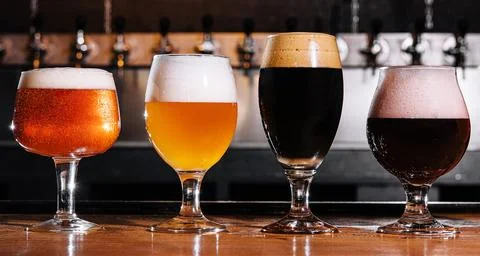 Different types of craft beer in glasses on table in pub interior Stock Photos