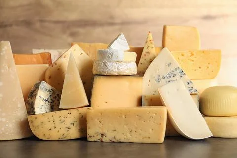 Different types of delicious cheese on table against wooden background Stock Photos