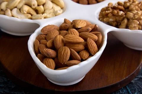 Different types of delicious nutritious nuts on a plate for a healthy snack Stock Photos