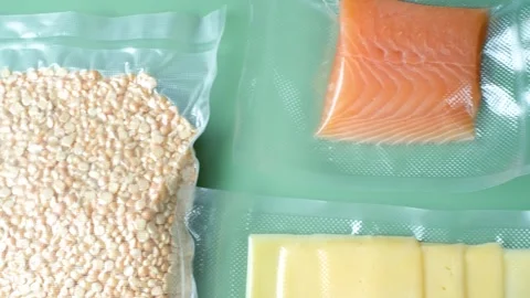 Different types of food packed in vacuum bags on green background top view. Stock Footage 280223117