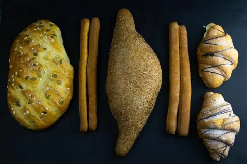 Different types of fresh bread with grain on a black rustic background. bread Stock Photos