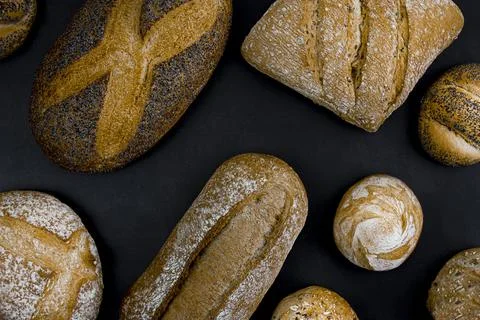 Different types of freshly baked bread on a black background. Stock Photos