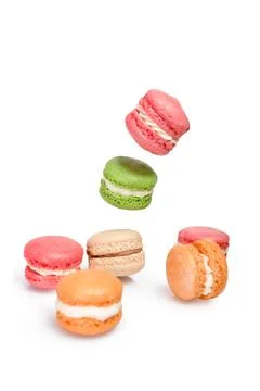 Different types of macaroons in motion falling or flying on white background. Stock Photos