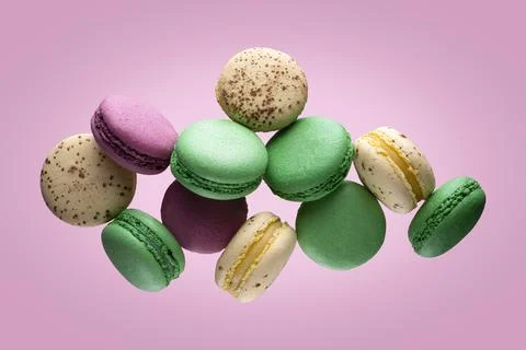 Different types of macaroons in motion falling on pink background. Stock Photos
