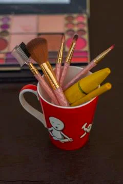 Different types of makeup brushes with muskcara and kajol pencil in a red mug Stock Photos
