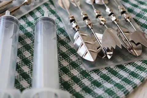 Different types of metal serving utensils arranged on a green checkered cloth Stock Photos