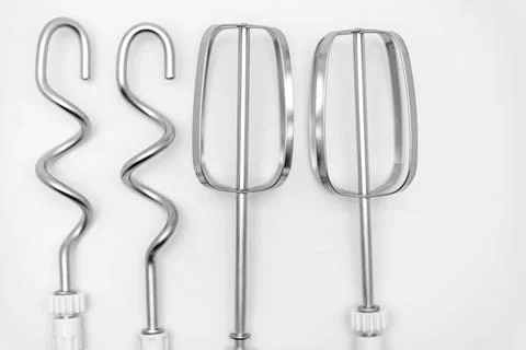 Different types of mixer attachments laid out on a white surface Stock Photos
