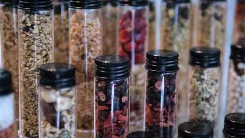 Different types nuts and dried fruits filled into identical glass jars lined up Stock Footage 276320728