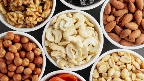 Different types of nuts and dried fruits rotating. Food in white bowls. 스톡 동영상 292393473