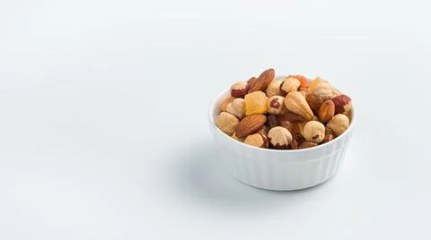 Different types of nuts and dried fruits in a white cup on a light background Stock Photos