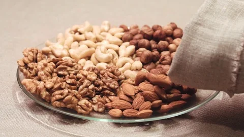 Different types nuts poured out of the sack into glass bowl Stock Footage 72118981