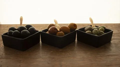 Different types of olives in three square black containers Stock Photos