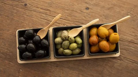 Different types of olives in three square black containers Stock Photos