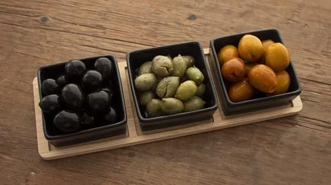 Different types of olives in three square black containers Stock Photos