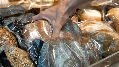 Different types of packaged bread on a wooden counter and a male hand takes one 動画素材 194156936