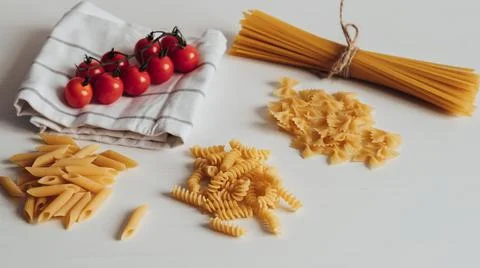 Different Types of Pasta and Cherry Tomatoes on the Kitchen Table Фото