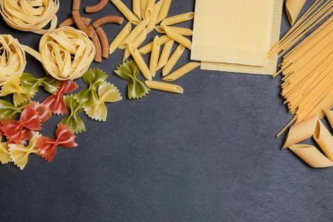 Different types of pasta on a black slate background with copy space. Top view Stock Photos
