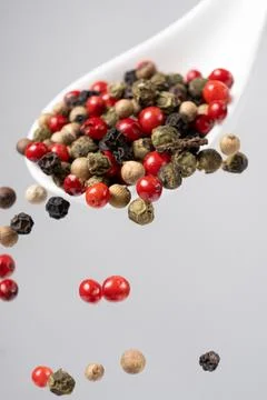 Different types of peppercorns pouring. Red, green, white and black pepper. Stock Photos