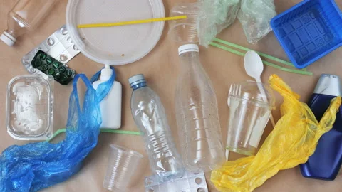 Different types of plastic garbage makes frame on craft paper background. Stock Footage 105528364
