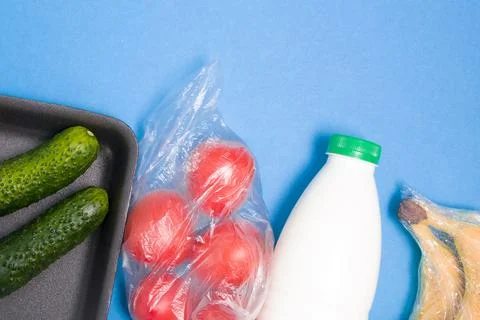 Different types of plastic packaging on a blue background, a tray with cucumb Stock Photos