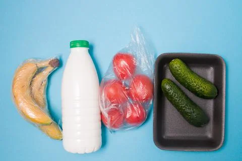 Different types of plastic packaging on a blue background, a tray with cucumb Stock Photos