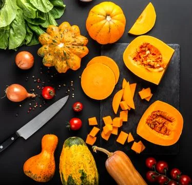 Different types of pumpkins and other vegetables on a black background. Top view Stock Photos