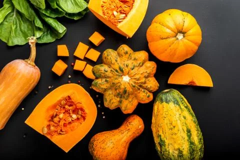 Different types of pumpkins on a black background. Top view. Stock Photos
