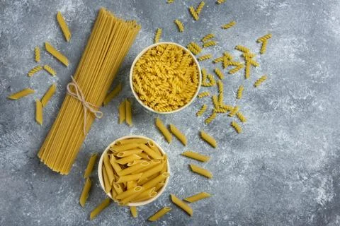 Different types of raw macaroni on a marble background Stock Photos