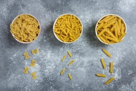 Different types of raw macaroni on a marble background Stock Photos