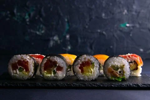 Different types of rolls stand on a black granite board for sushi on a black  Stock Photos