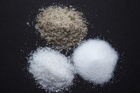 Different types of salt on a black background. Stock Photos