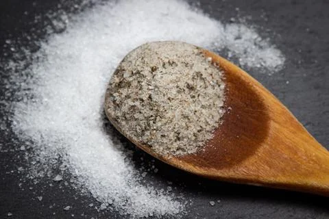 Different types of salt. Salt with spices and pure salt on a dark background. Stock Photos