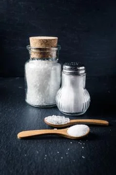 Different types of salt with spoons and jars on dark background. Sea salt Stock Photos
