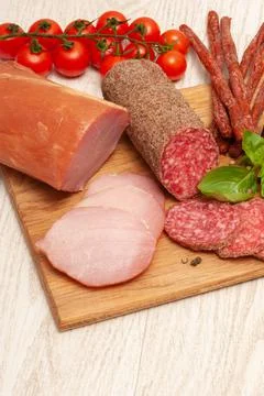 Different types of sausages with tomatoes and herbs on a wooden board. Top view Stock Photos