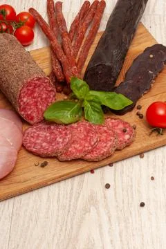 Different types of sausages with tomatoes and herbs on a wooden board. Top view Stock Photos