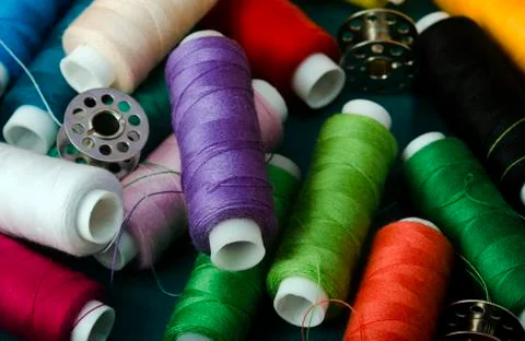 Different types of sewing threads pilled on Green Fabric. Stock Photos
